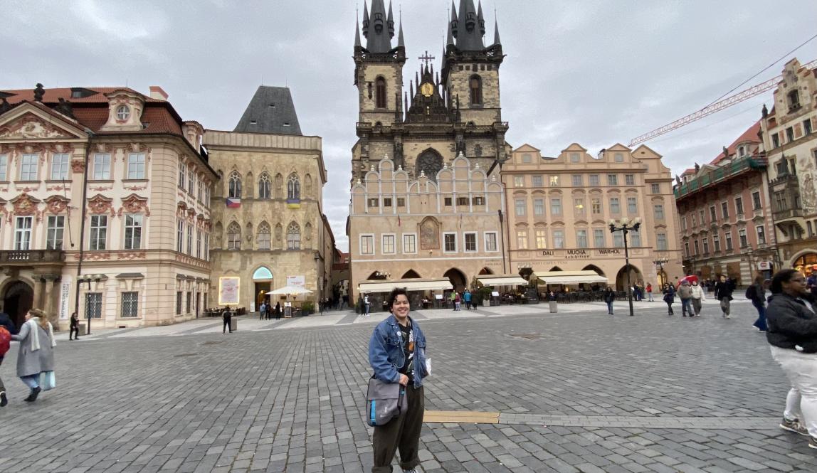 Me (a short white man with a denim jacket and green pants) in the middle of Prague old town, surrounded by gothic buildings. It is in 0.5 view so I look smaller than I am.