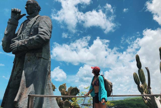 a student staring up at a giant statue of Charles Darwin