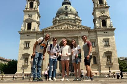Image shows five young adults (3 male, 2 female) in front of St. Stephen's Basilica in Budapest, Hungary.