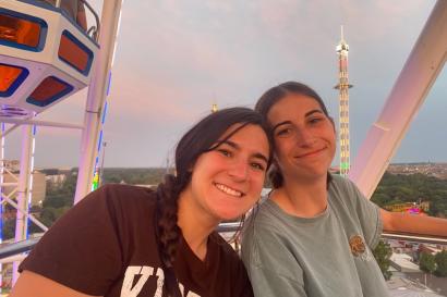 Two girls together on a ferris wheel smiling at sunset