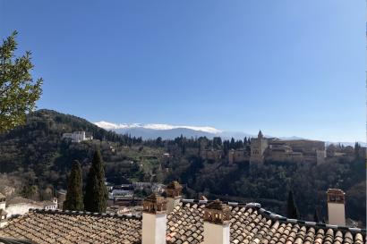 A view of the Alhambra with rooftops in foreground and Sierra Nevada visible in the background 