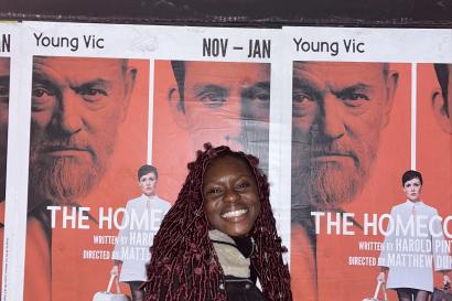 me standing in front of a poster for "The Homecoming" play at the Young Vic Theatre in London 