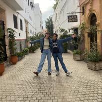 Two friends posing on a street lined with plants in Rabat's Old Medina