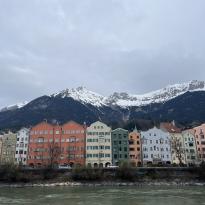 colorful houses line the street in Innsbruck with mountains hovering over