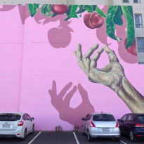 Bright pink mural with an image of a hand reaching up for a dangling plum
