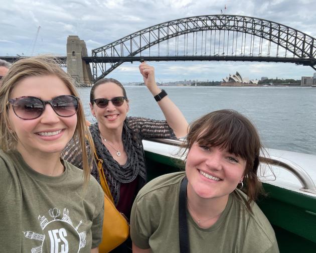 staff members on a boat in front of a bridge over looking water smiling
