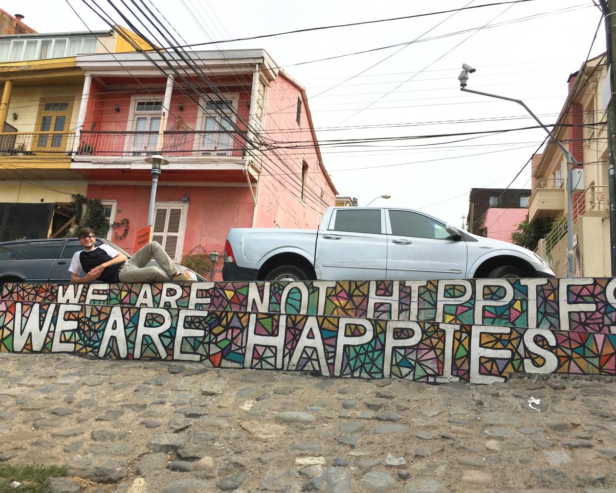 A student lies on a wall that says "we are not hippies, we are happies"