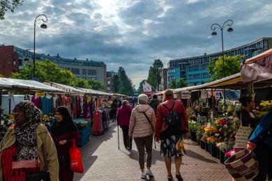 Couples walk down a market in Amsterdam lined on either side with vendors.