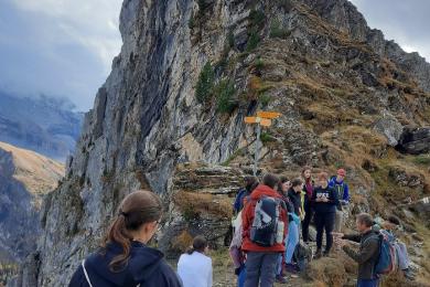 a line of students with a professor walking up the peak of a mountain range