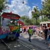 This is an image of a tram in Vienna decorated in the color of the rainbow for pride and attendees of the pride parade.