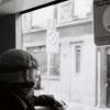 A masked person looks out a tram window