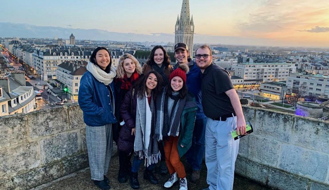 a group of friends pose for a photo on a rooftop with a nice city background in Nantes