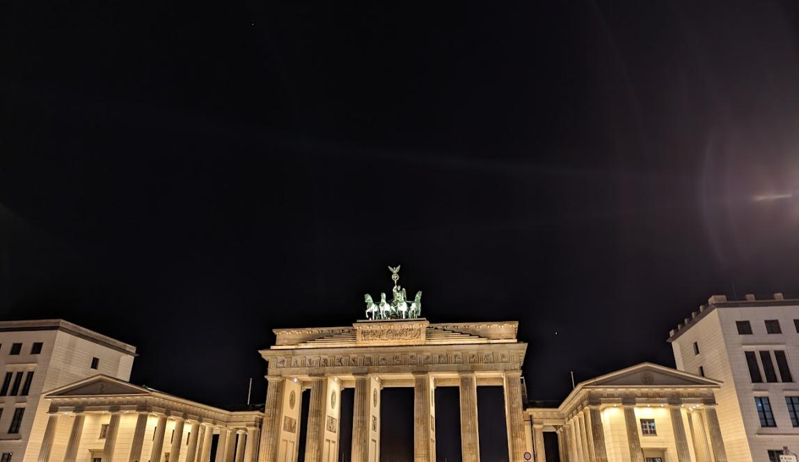 Brandenburger Tor lit up at night with a crowd in front of it
