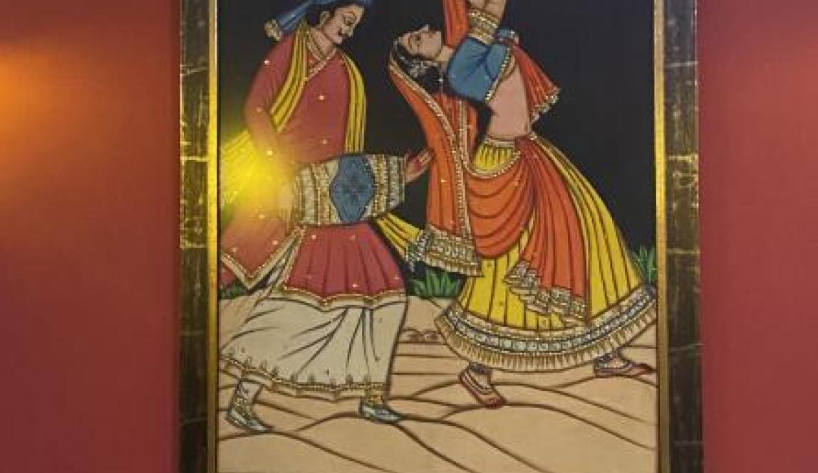 A picture of one of the Indian paintings framed and hung up as decoration in the Indian restaurant. It shows a woman dancing and a man behind her playing the drums.