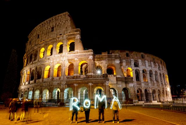 students use sparklers to spell out "ROMA" in front of the Colosseum in Rome