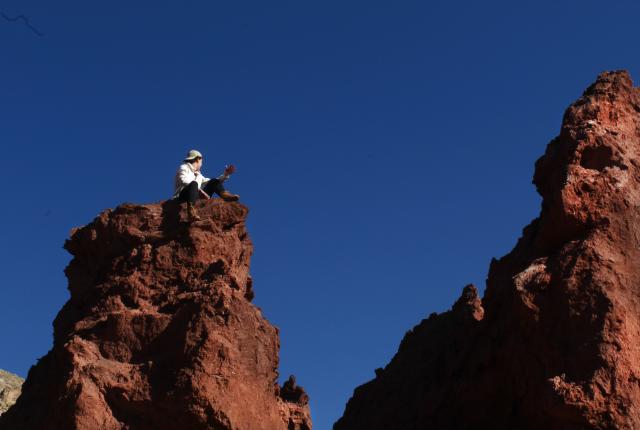 A students sits on the top of a rock.