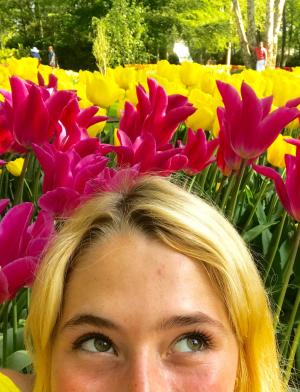 a student's face from their eyes up in front of pink and yellow tulips