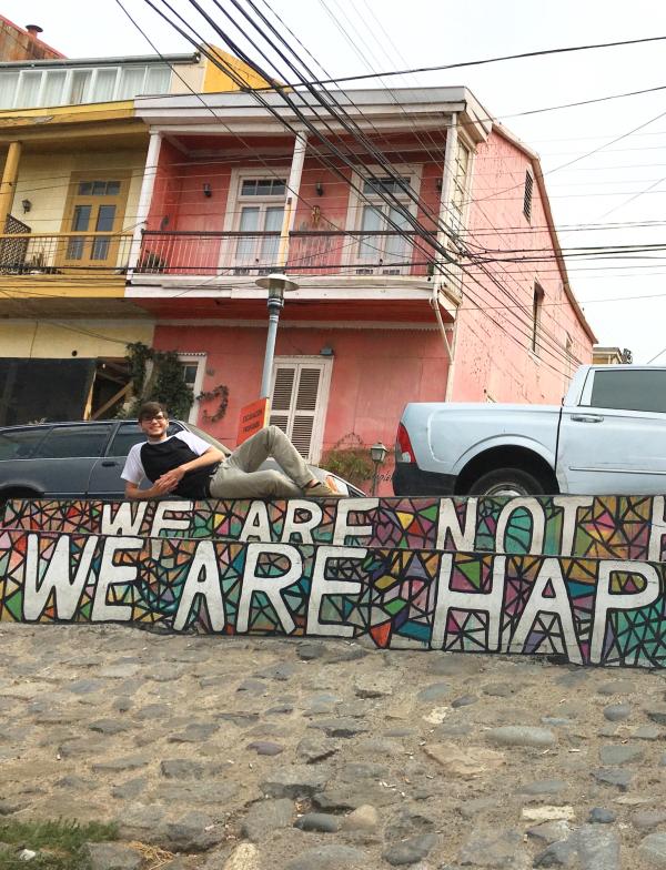A student lies on a wall that says "we are not hippies, we are happies"