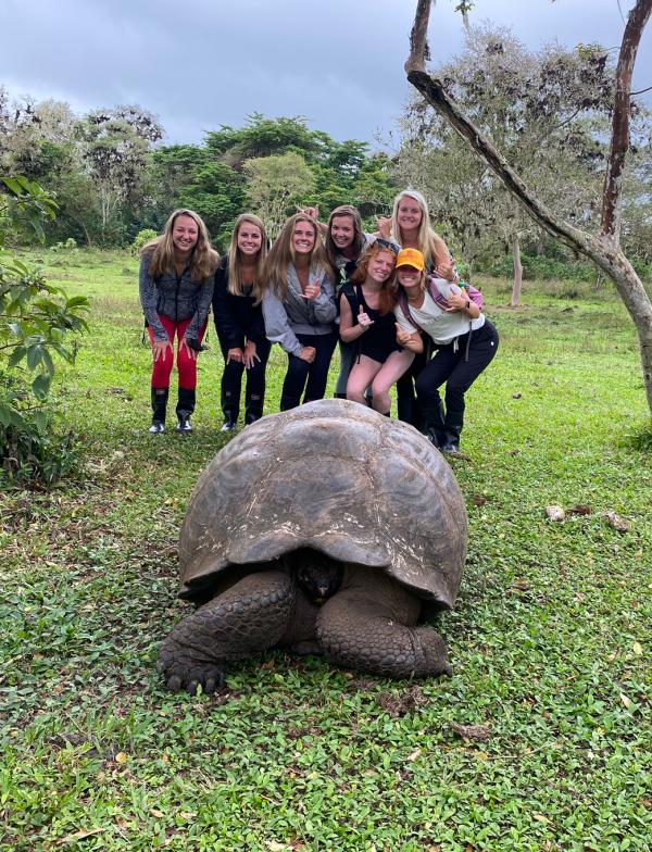 Students pose with a Giant Galapagos Tortoise on the Santa Cruz Island, Ecuador. 