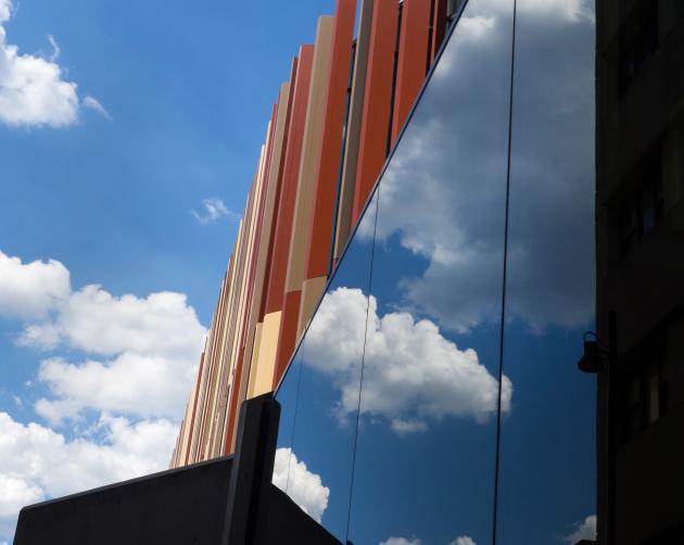 An artistic shot of the Macquarie Library. A window reflects the blue sky with puffy white clouds.