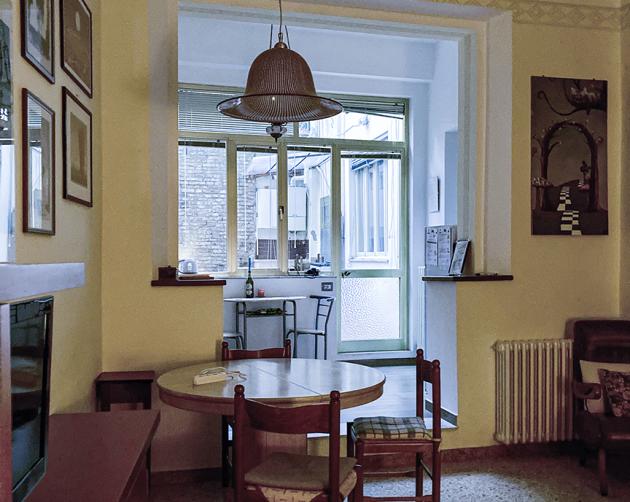 A living room with pale yellow walls, a dining room table, and large windows.