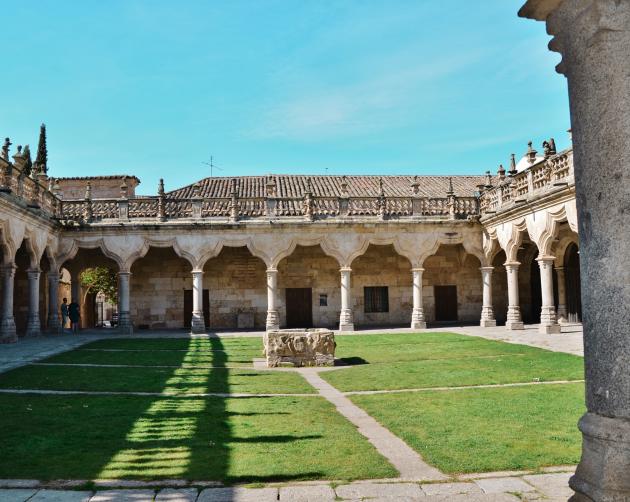 The courtyard at the University of Salamanca. Grass is surrounded by Spanish arch pillars.