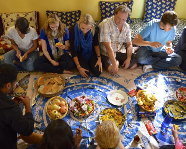 a group of people in Rabat sitting on the floor to eat dinner
