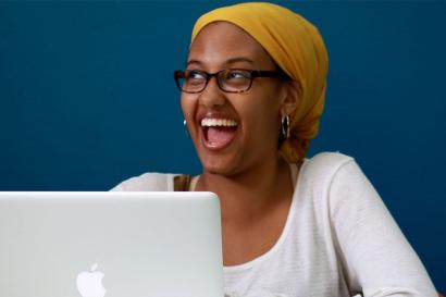 A girl using a laptop and smiling 