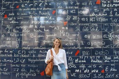 a girl standing near the wall with text and looking at the camera person 