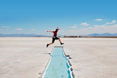 Student jumping over a little river in the salt flats