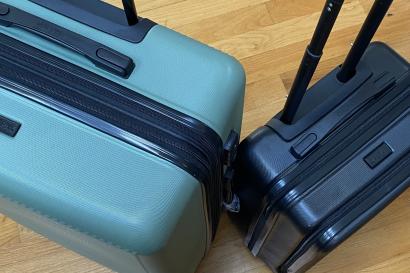 Large green suitcase on the left located next to smaller black suitcase on the right. 