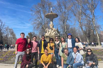 Group of people standing in front of fountain posing for picture. 