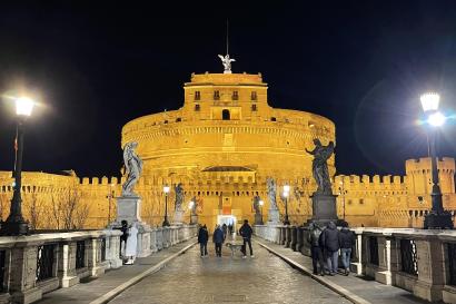 Castel Sant'Angelo is illuminated by bridge lights in the dead of night.