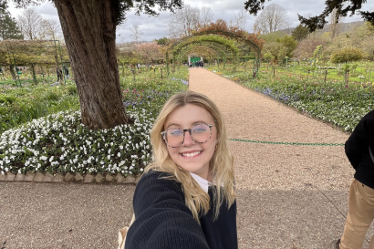 Blonde young woman wearing glasses takes selfie smiling in Monet's Garden.