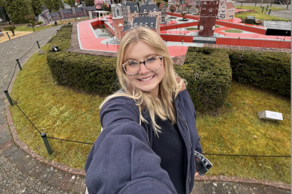 Blonde girl takes a selfie smiling in front of miniature monuments in Brussels, Belgium.