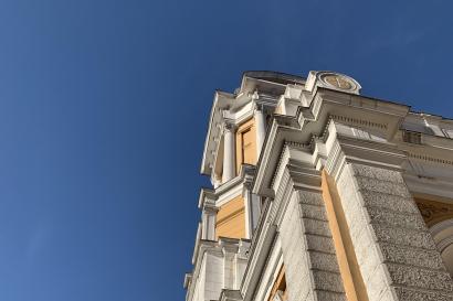 A tall, light yellow Catholic Church with white pillars and accents stands out against a blue sky.