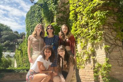 5 girls in front of arches with green plants growing on them