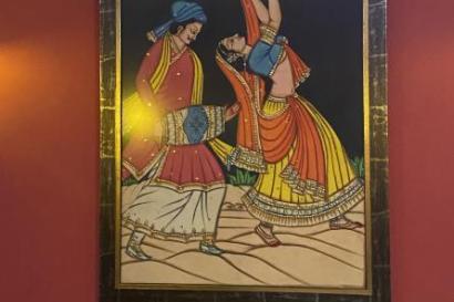 A picture of one of the Indian paintings framed and hung up as decoration in the Indian restaurant. It shows a woman dancing and a man behind her playing the drums.