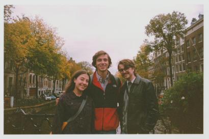 Three students, two men and one woman, stand in front of a canal. The photo has a vintage look to it