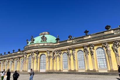 Yellow palace with greenish dome stands in front of blue sky
