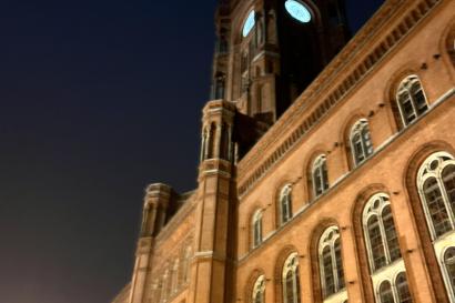 Large red building at night with clock tower with glowing clock face
