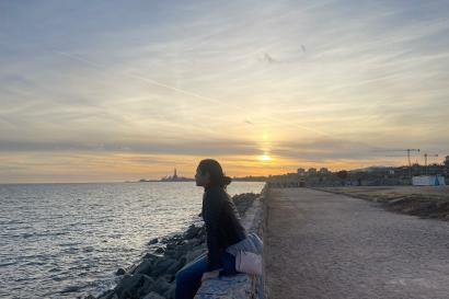 girl sitting on wall looking at the sea