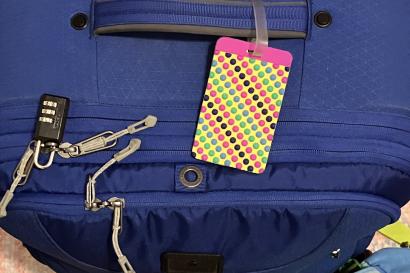Picture of a dark blue suitcase with a polka-dot luggage tag, seen from the top