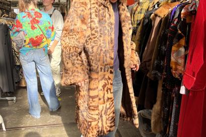 Person wearing fur cheetah-print coat in flea market