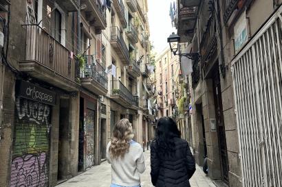 Two girls look up in awe of the towering buildings as they walk through an alley in the Gothic Quarter. 