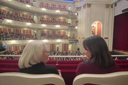 A young woman and older woman talk in an opera house