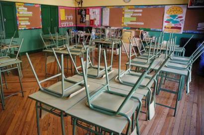 An empty classroom from a newspaper article. Chairs rest upside-down on desks.