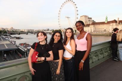 A group of friends smiling on a bridge in front of the London Eye
