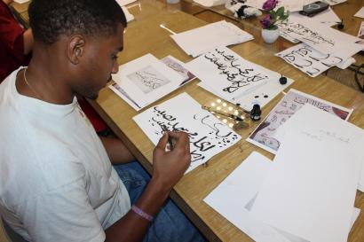 A photo of a student writing in Arabic in caligraphy in Meknes, Morocco