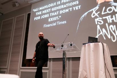 A smiling man standing on a stage with a microphone